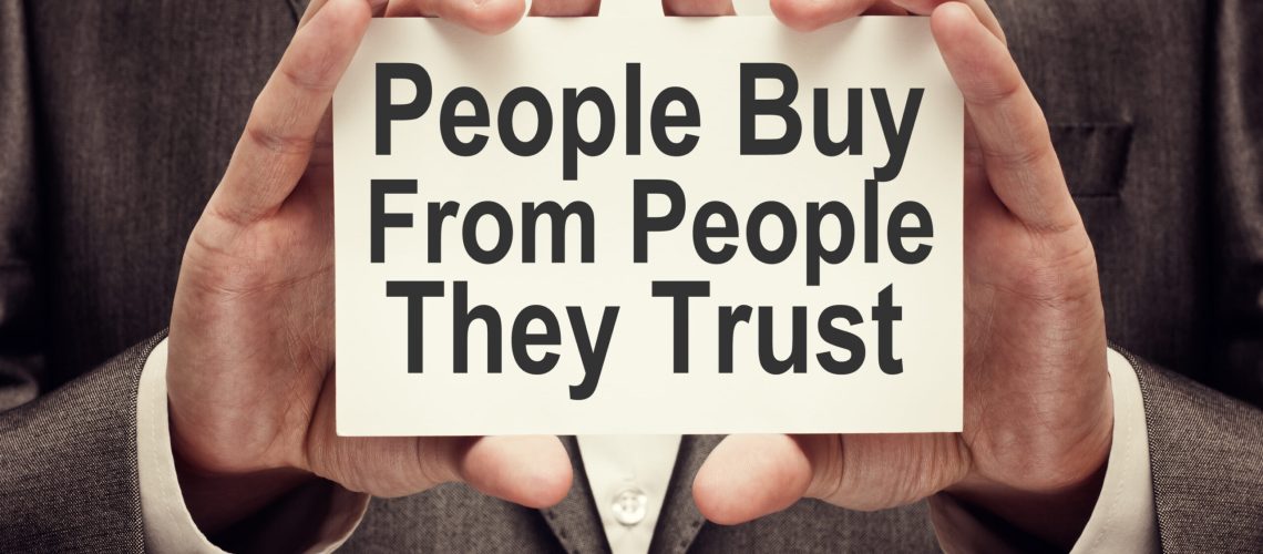 People Buy From People They Trust. Businessman holding a card with a message text written on it